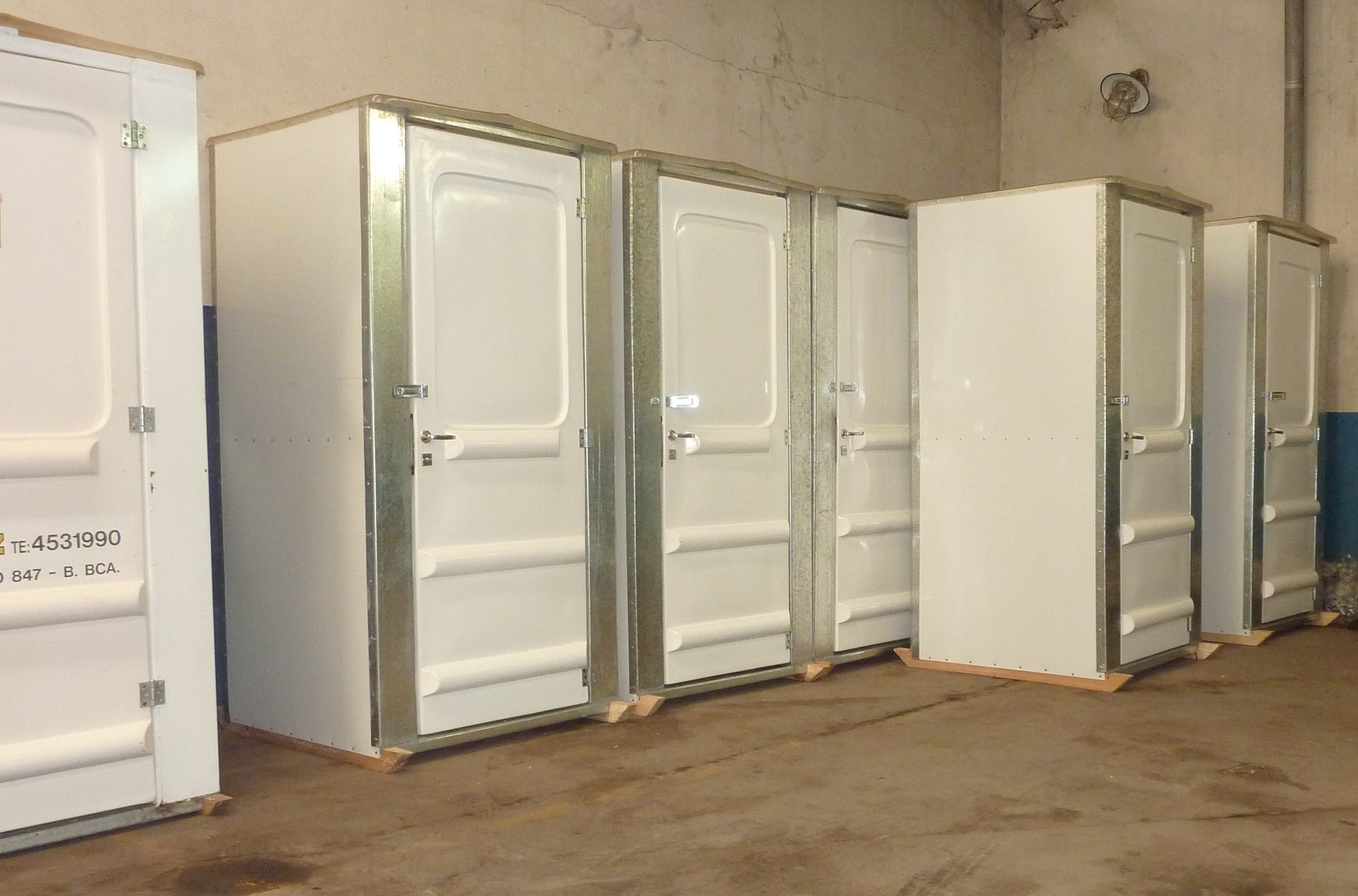 Baños portátiles blancos exhibidos en un galpón